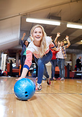 Image showing happy young woman throwing ball in bowling club