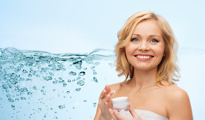 Image showing happy middle aged woman with moisturizing cream