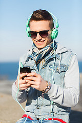 Image showing happy young man in headphones with smartphone