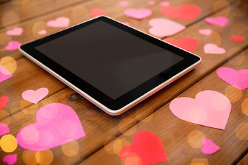 Image showing close up of tablet pc and hearts on wood