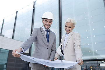 Image showing smiling businessmen with blueprint and helmets