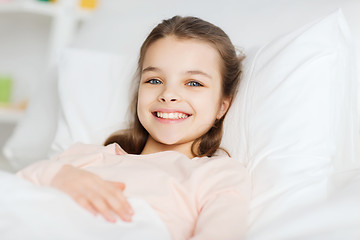 Image showing happy smiling girl lying awake in bed at home