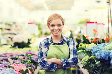 Image showing happy woman with flowers in greenhouse