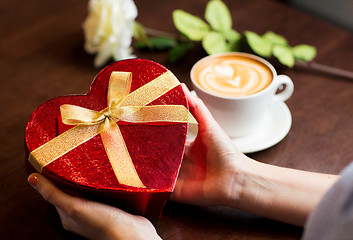 Image showing close up of hands holding heart shaped gift box