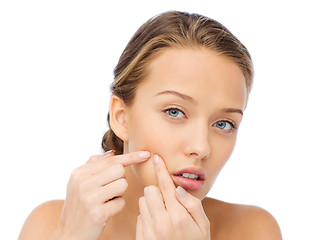 Image showing young woman squeezing pimple on her face