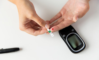 Image showing close up of woman making blood test by glucometer