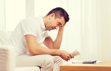 Image showing man with money and calculator at home