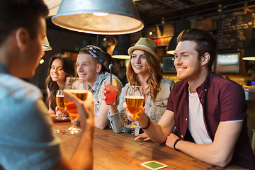 Image showing happy friends with drinks talking at bar or pub