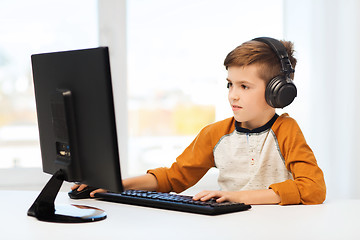 Image showing happy boy with computer and headphones at home