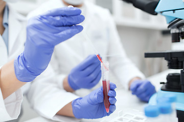 Image showing close up of scientists filling test tube in lab