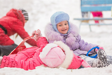 Image showing The girl with a smile looking at another girl rolled down the hills