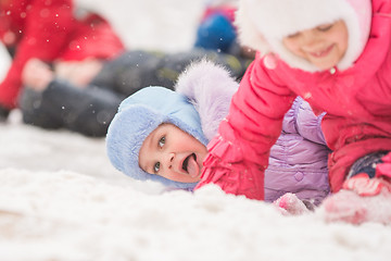 Image showing Girl showing tongue rolled down a hill and fell into the snow