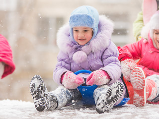 Image showing Happy little girl getting ready to roll down the icy hill