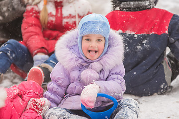 Image showing  Five-year girl sitting in the snow surrounded by other children
