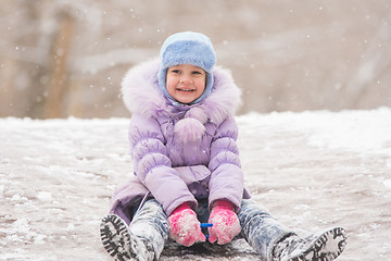 Image showing Joyful five years girl rolls down from the icy hill