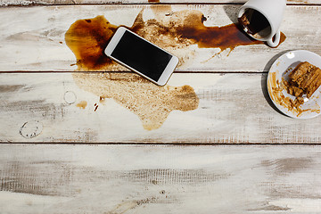 Image showing Cup of coffee spilled on wooden table