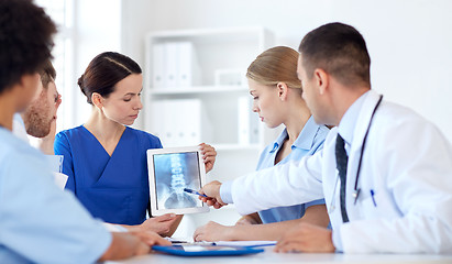 Image showing group of doctors with x-ray on tablet pc at clinic