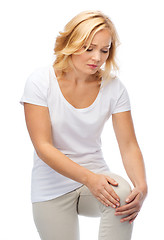 Image showing unhappy woman suffering from pain in leg