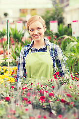 Image showing happy woman with flowers in greenhouse