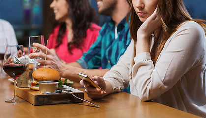 Image showing woman with smartphone and friends at restaurant