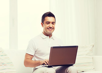 Image showing happy man working with laptop computer at home