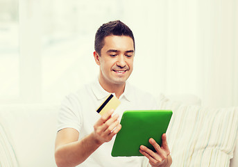 Image showing smiling man working with tablet pc at home