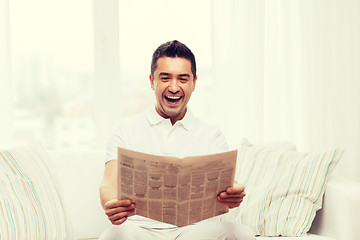Image showing happy man reading newspaper and laughing at home