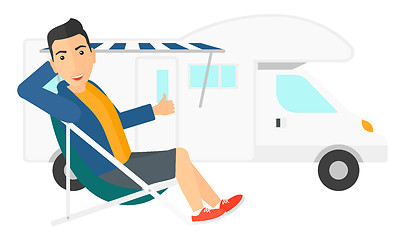 Image showing Man sitting in front of motorhome.