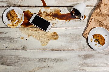 Image showing Cup of coffee spilled on wooden table