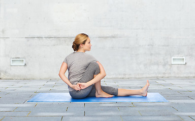 Image showing woman making yoga in twist pose on mat outdoors