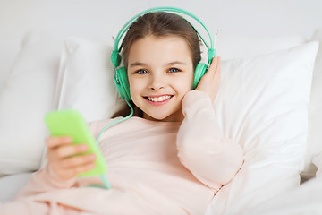 Image showing happy girl lying in bed with smartphone at home