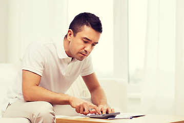 Image showing man with papers and calculator at home