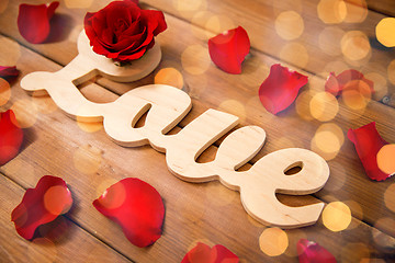 Image showing close up of word love cutout with red rose on wood