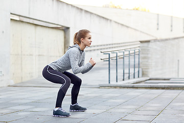 Image showing woman doing squats and exercising outdoors