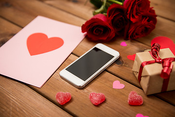 Image showing close up of smartphone, gift, red roses and hearts