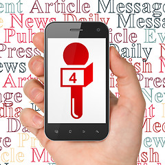 Image showing News concept: Hand Holding Smartphone with Microphone on display