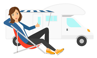 Image showing Woman sitting in front of motorhome.