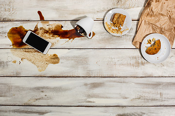 Image showing Cup of coffee spilled on wooden table