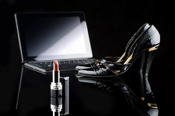 Image showing laptop, lipstick and shoes. black background. female set. Online buying cosmetics