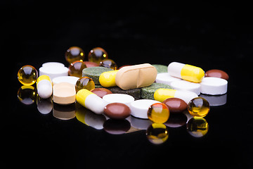 Image showing Pile of various colorful pills isolated on black