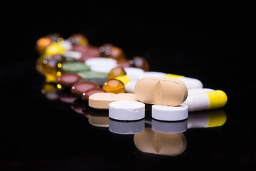 Image showing Pile of various colorful pills isolated on black