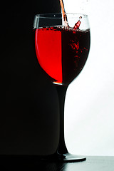 Image showing Red wine pouring. white on black background