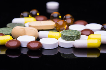 Image showing Pile of various colorful pills isolated on black