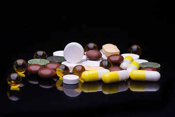 Image showing Pile of various colorful pills isolated on black