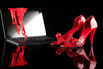 Image showing laptop, clothes, and shoes on black background. Women set. Online buying lingerie