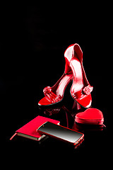 Image showing red phone, women\'s high-heeled shoes and a notebook. set. black background. 