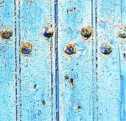 Image showing stripped paint in the blue wood door and rusty nail