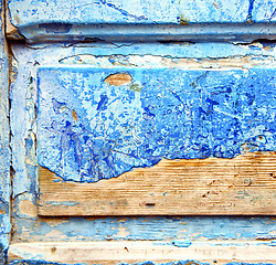 Image showing dirty stripped paint in the blue wood door and rusty nail