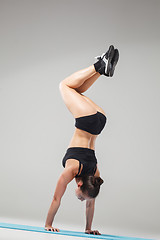 Image showing Beautiful sporty girl standing in acrobat pose or yoga asana