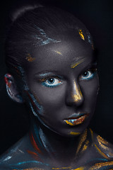 Image showing Portrait of a young woman who is posing covered with  black paint 